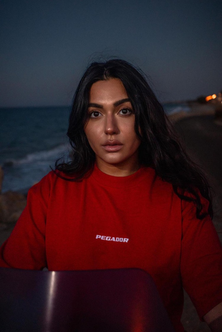 Roter Pullover am Strand in der Dämmerung, Wellen dahinter.